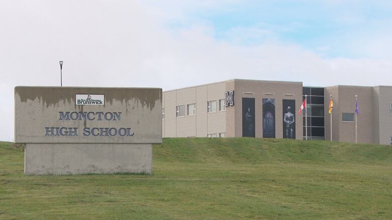 A grey stone building stands on a grassy hill.