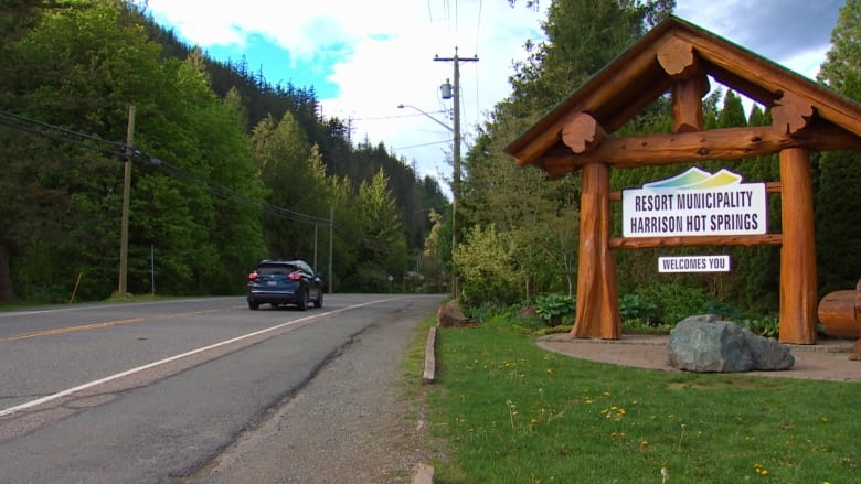 A road with a sign on the right that says Resort Municipality Harrison Hot Springs.