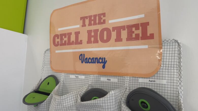 A sign reads The Cell Hotel, Vacancy. Underneath are cubby holes, for students to place their phones inside. 