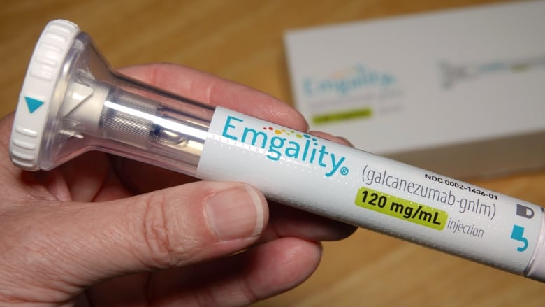 Close up of hand holding Emgality auto-injector.