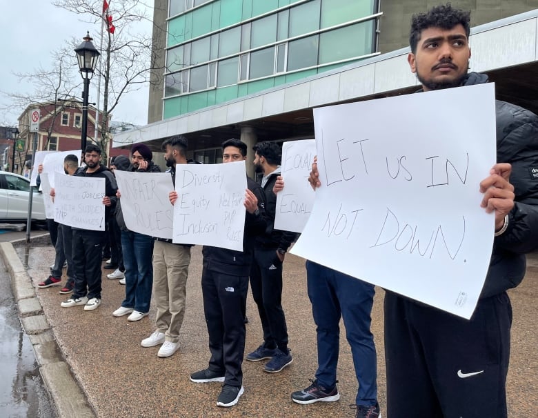 A row of protesters holding signs outside in the rain.