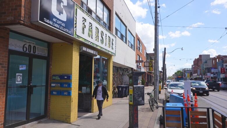 A view of a bar from the side walk. A man walks by. 