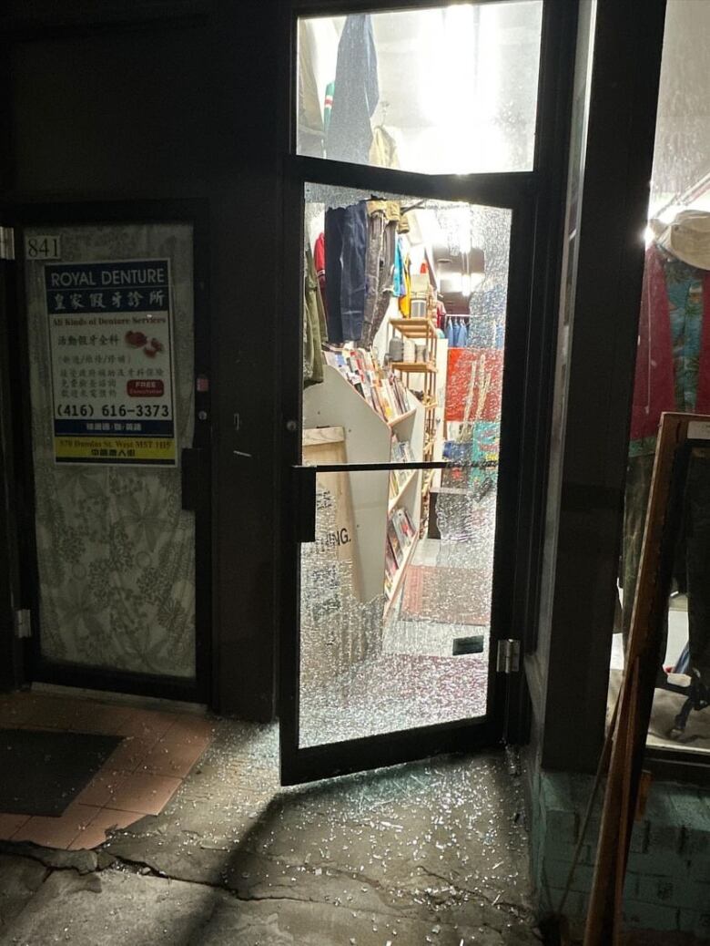 A photo of small clothing store with a smashed glass door.