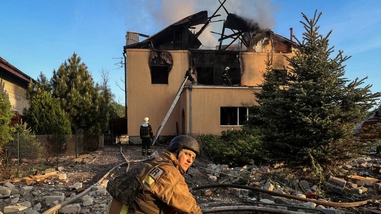 Firefighters work on a tan-coloured house after it was hit by a missile.