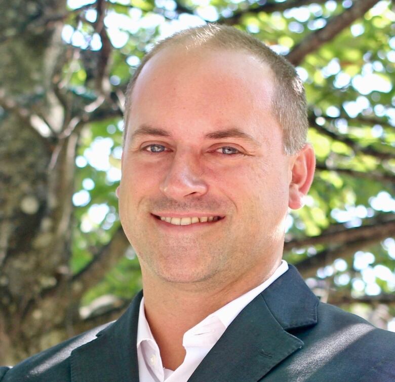 A clean-shaven man smiles at the camera.