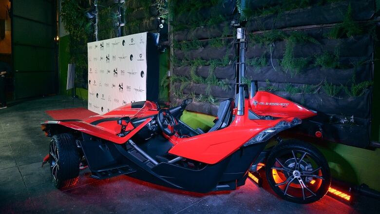 a red car with three wheels at an award show 