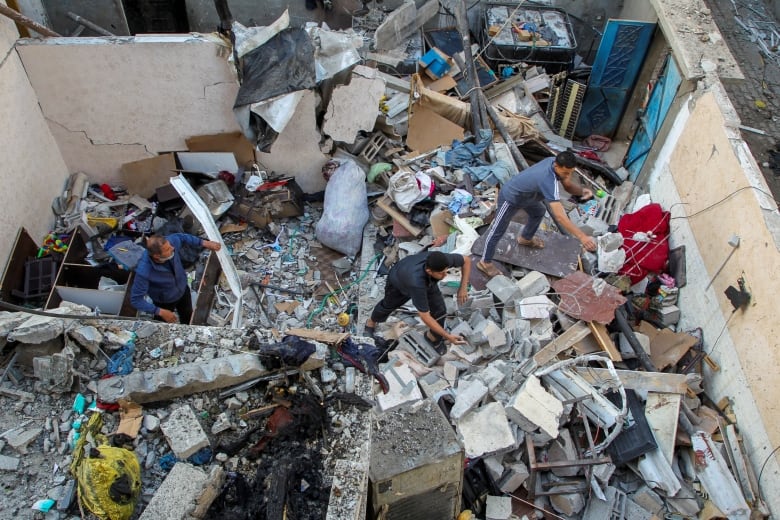 Several men sift through concrete rubble after a house was destroyed by an airstrike.