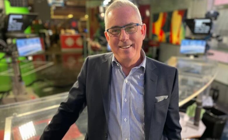 A man wearing a blazer stands in the CBC Ottawa television studio.