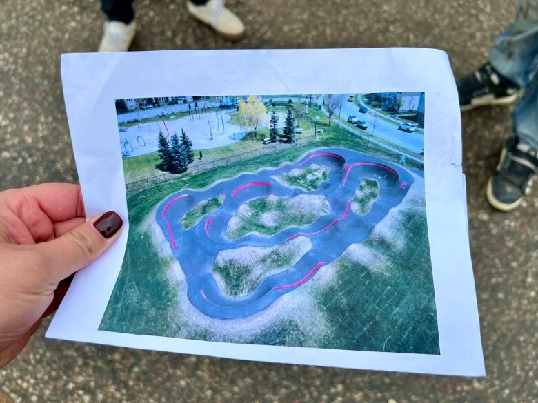 A person holding a photo of a pump track