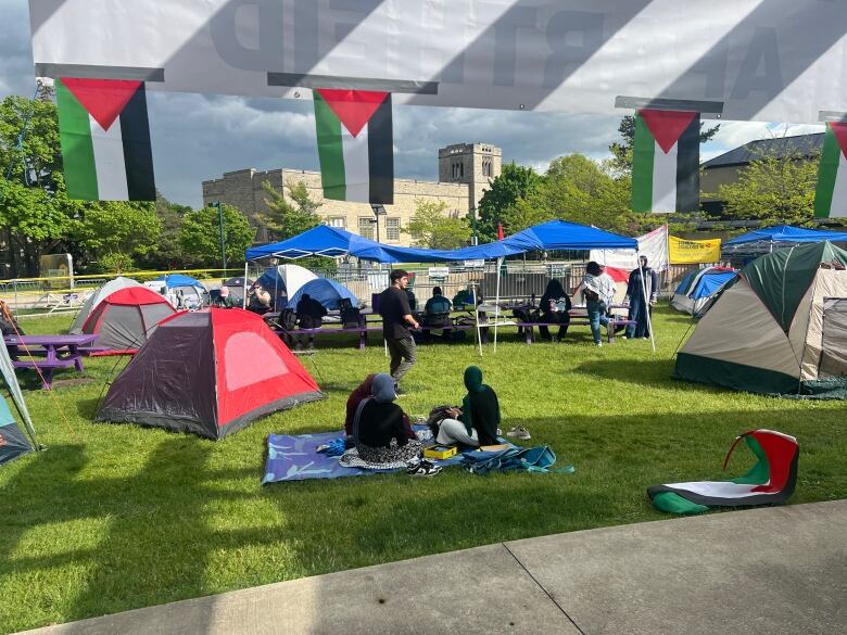 people sit on blankets near tents on grass at Western University