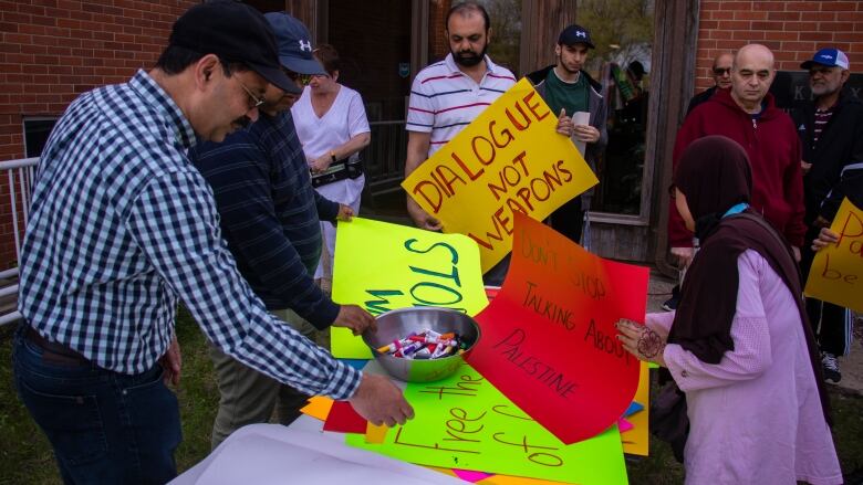 People gather around a table holding posters.