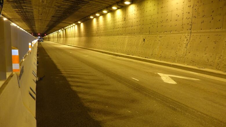 Shot of an empty traffic tunnel. One construction truck can vaguely be seen in the distance. 