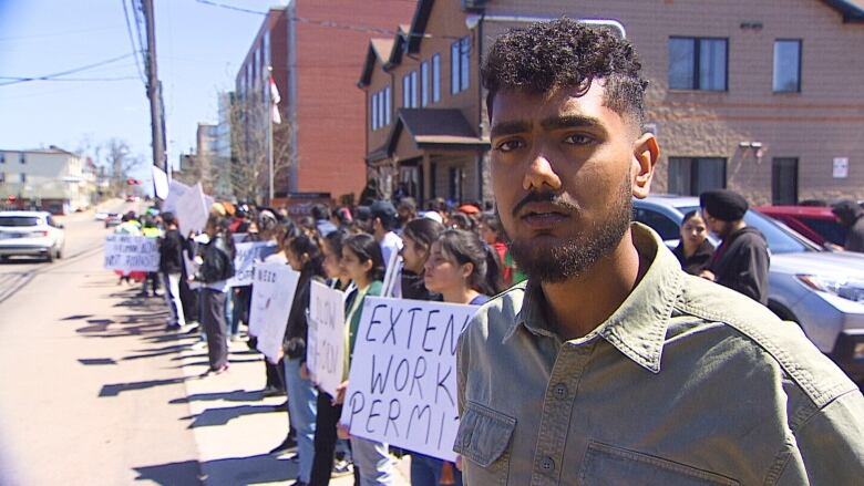 People lining streets with signs protesting immigration policy.