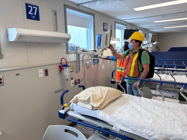 two people work on hospital equipment