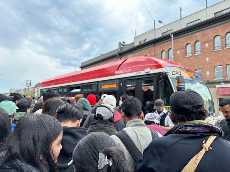 TTC customers crowd together as a shuttle bus approaches on Danforth Avenue near Broadview Avenue.