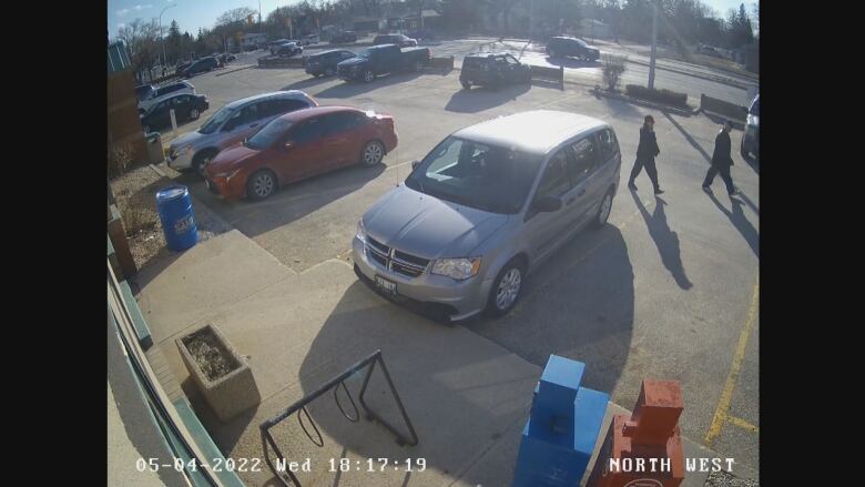 Two people walk in a parking lot seen in surveillance video.