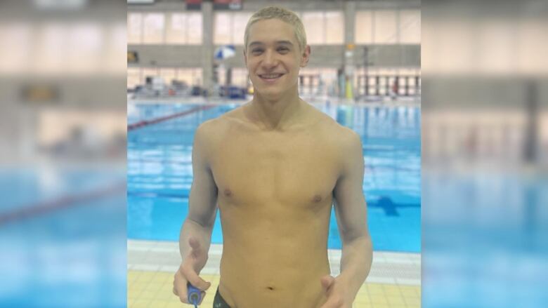 A man stands by an indoor pool and smiles.