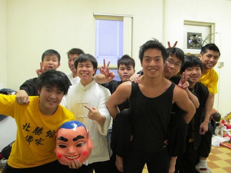 A group of black-haired young boys flash peace signs at a camera.