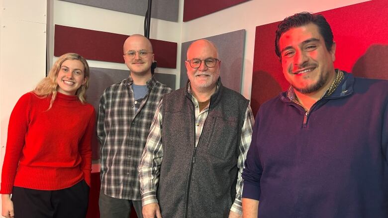 1 Woman and 3 men stand together with a red and gray background.