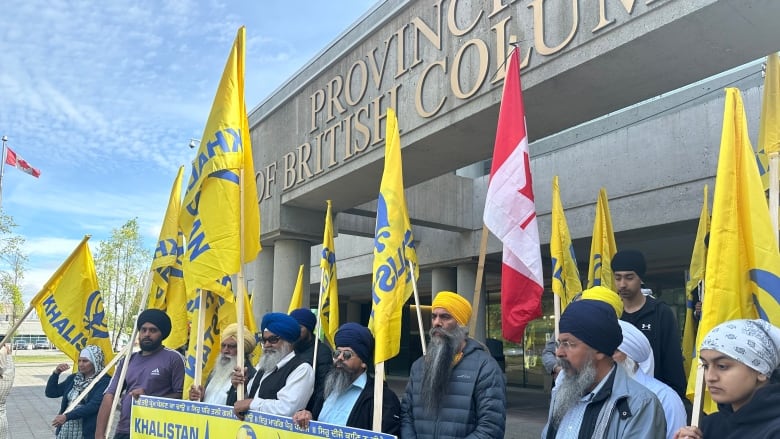 Protestors stand outside a courthouse in Surrey, B.C. prior to an appearance of one of four men charged with murder in the death of slain Sikh leader Hardeep Singh Nijjar.