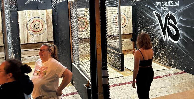 A person wearing a tank top gets ready to throw an axe at a target