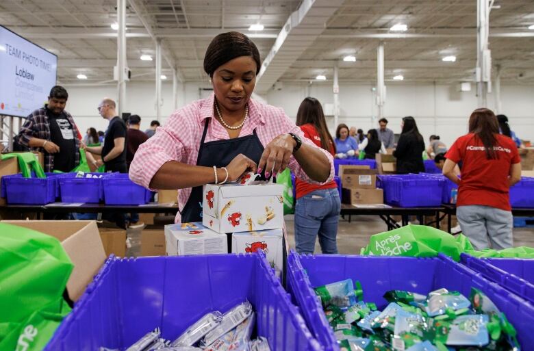 A volunteer opens a box during a Food Banks Canada packing drive at the International Centre in Mississauga, Ont., on May 15, 2024.