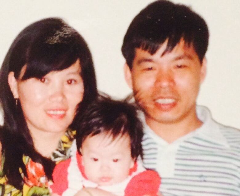 Two adults pose for a photo with a baby.