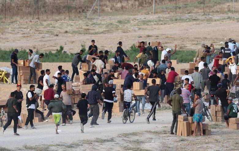 People carry boxes in a field.