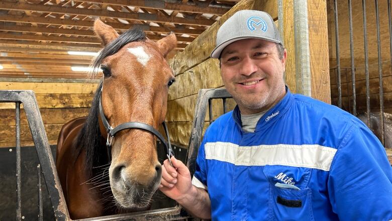 Man in stable with horse.