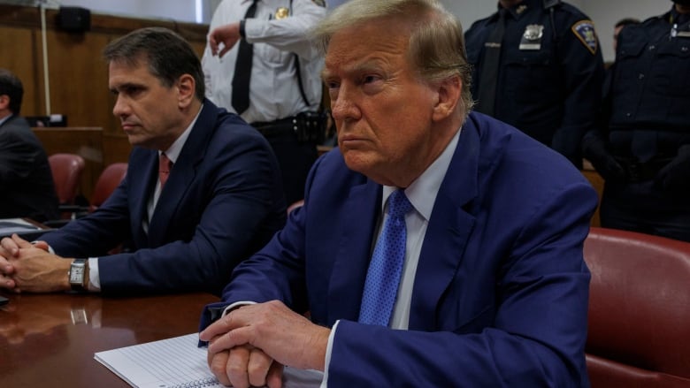 A man sits at a table in a courtroom.