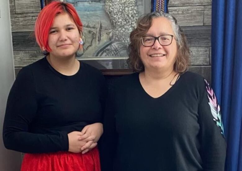 A girl standing next to her grandmother.