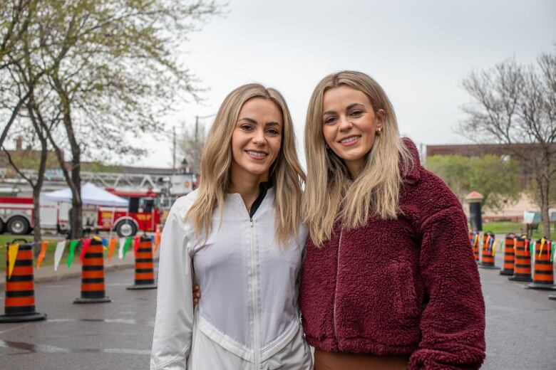 Two people are seen standing on a road, smiling.