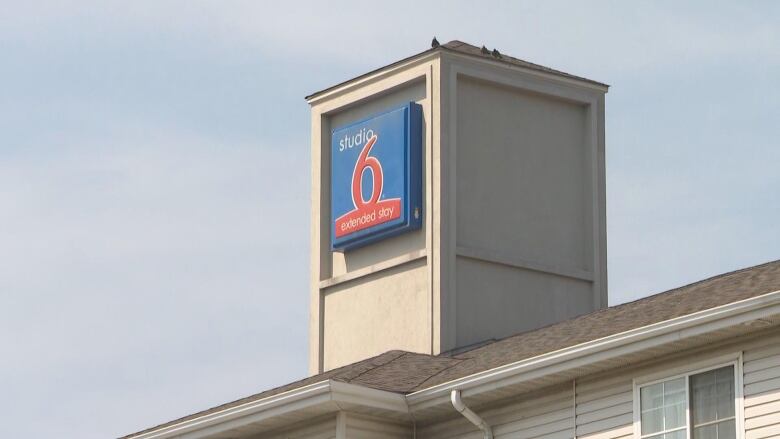 A blue sign above a hotel, reading Studio 6. 