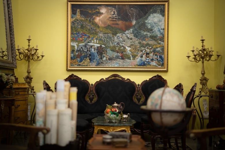 a black antique sofa is surrounded by candles, a tea table, a globe and maps