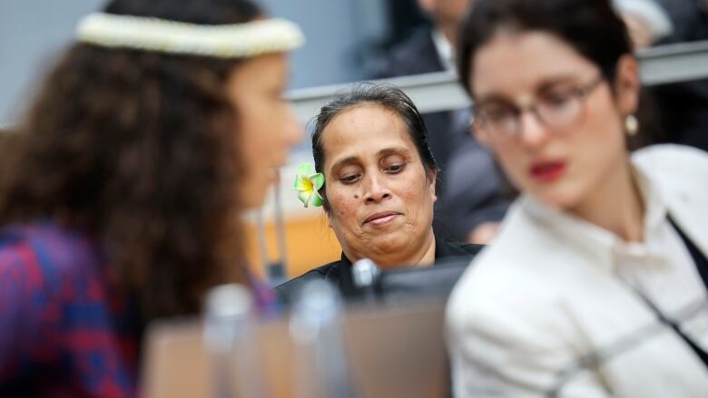 A representative with a flower in her hair and other representatives of a group of nine small island states in the Pacific and Caribbean sit in a courtroom.