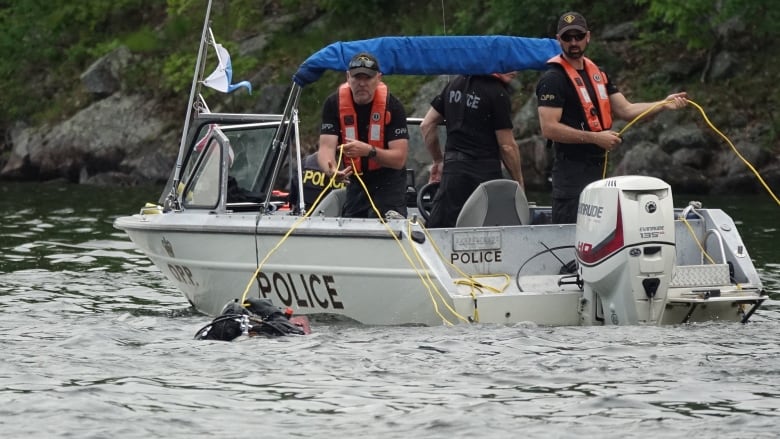 A police boat and divers in the water.