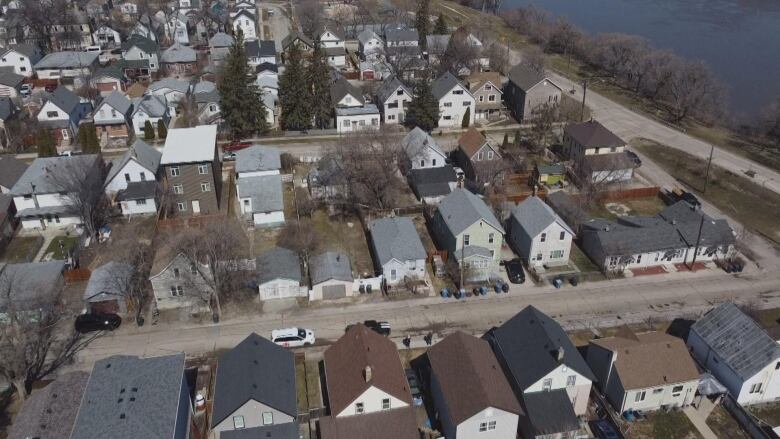 An aerial shot shows rows of streets with houses, and a river to the right.