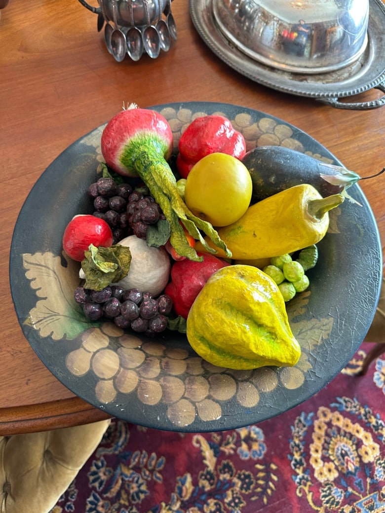 A set of wax fruits and vegetables, including root vegetables and grapes.