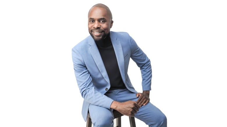 A portrait of a man sitting on a stool in a suit. 