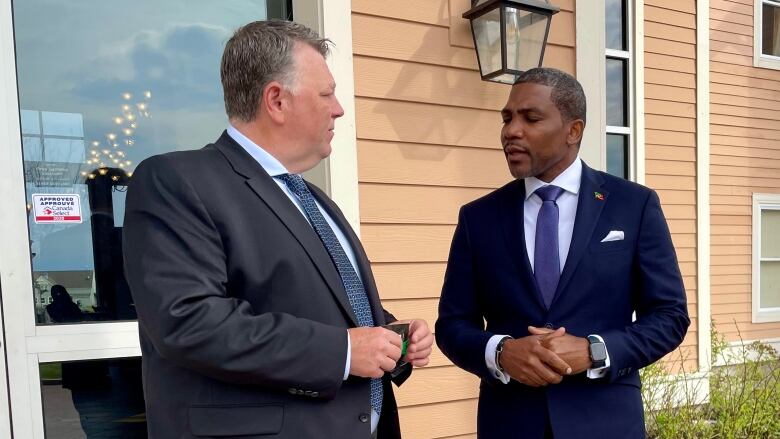 Premier Dennis King speaking with man in blue suit.