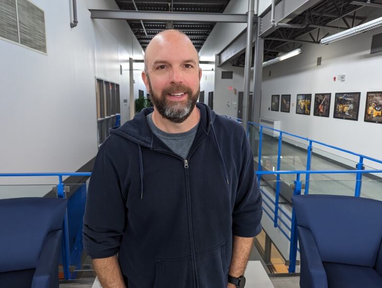 A bald man with a beard wearing a blue hoodie.