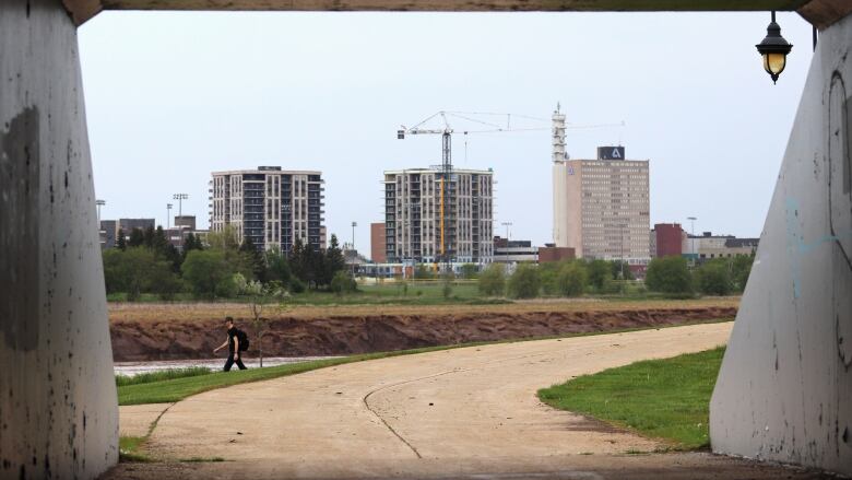 Several tall buildings with a crane viewed through a tunnel opening. 