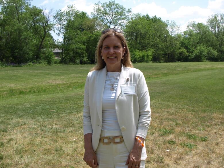 A woman stands on grass.