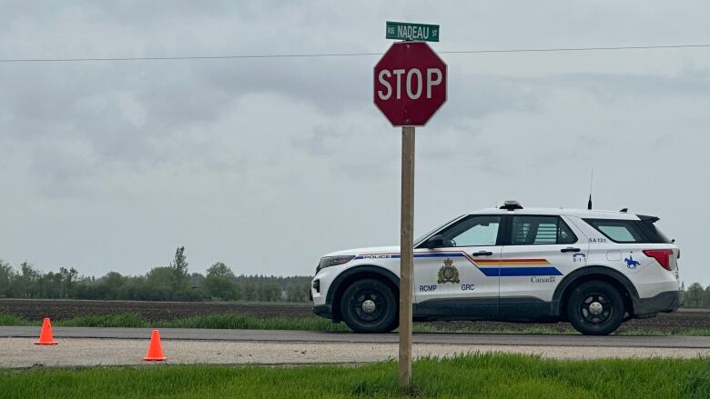 An RCMP vehicle is parked at a stop sign on a highway. 