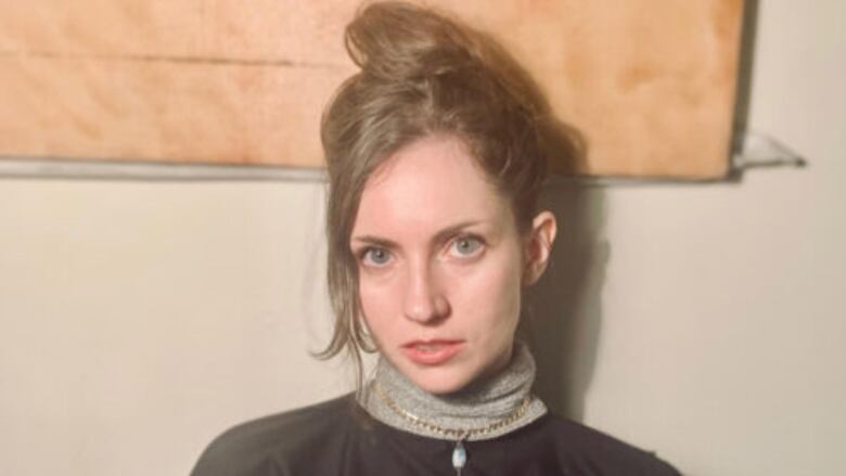 A woman with a messy bun wearing a turtleneck. 