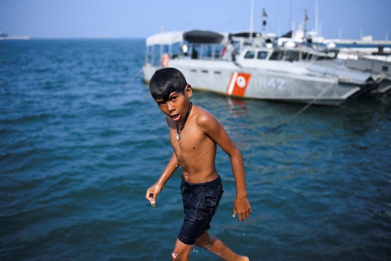 A boy walks alongside the ocean