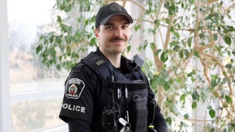 A police officer with a moustache in full uniform.