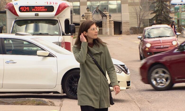 A woman tucks her hair behind her ear as she walks down a street in Calgary. 