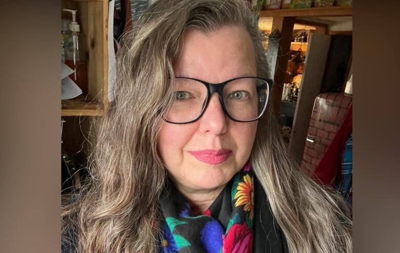 Woman with glasses smiles in a closeup.