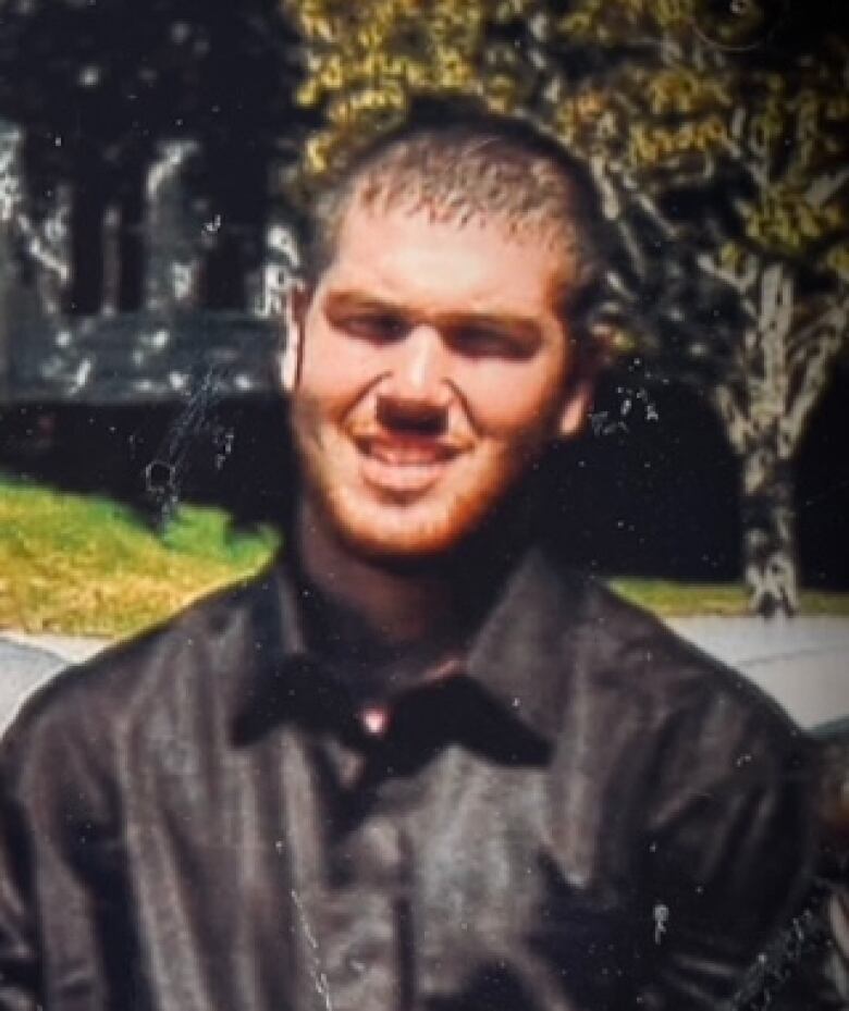 A young man in a black leather jacket squints at the camera